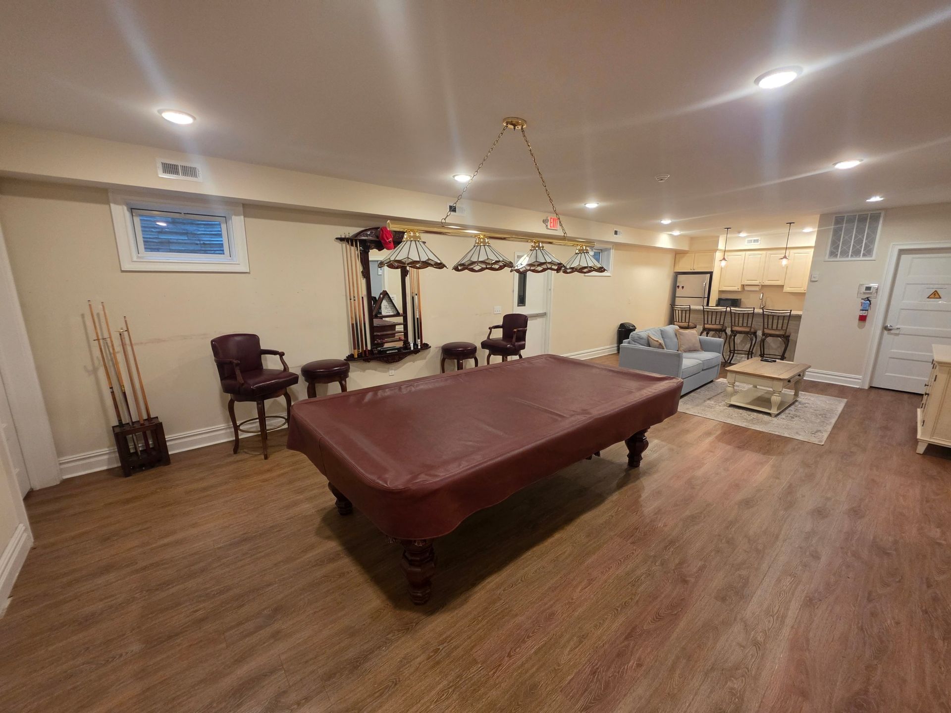 Lower-level game room with a billiard table, cue racks and leather bar chairs