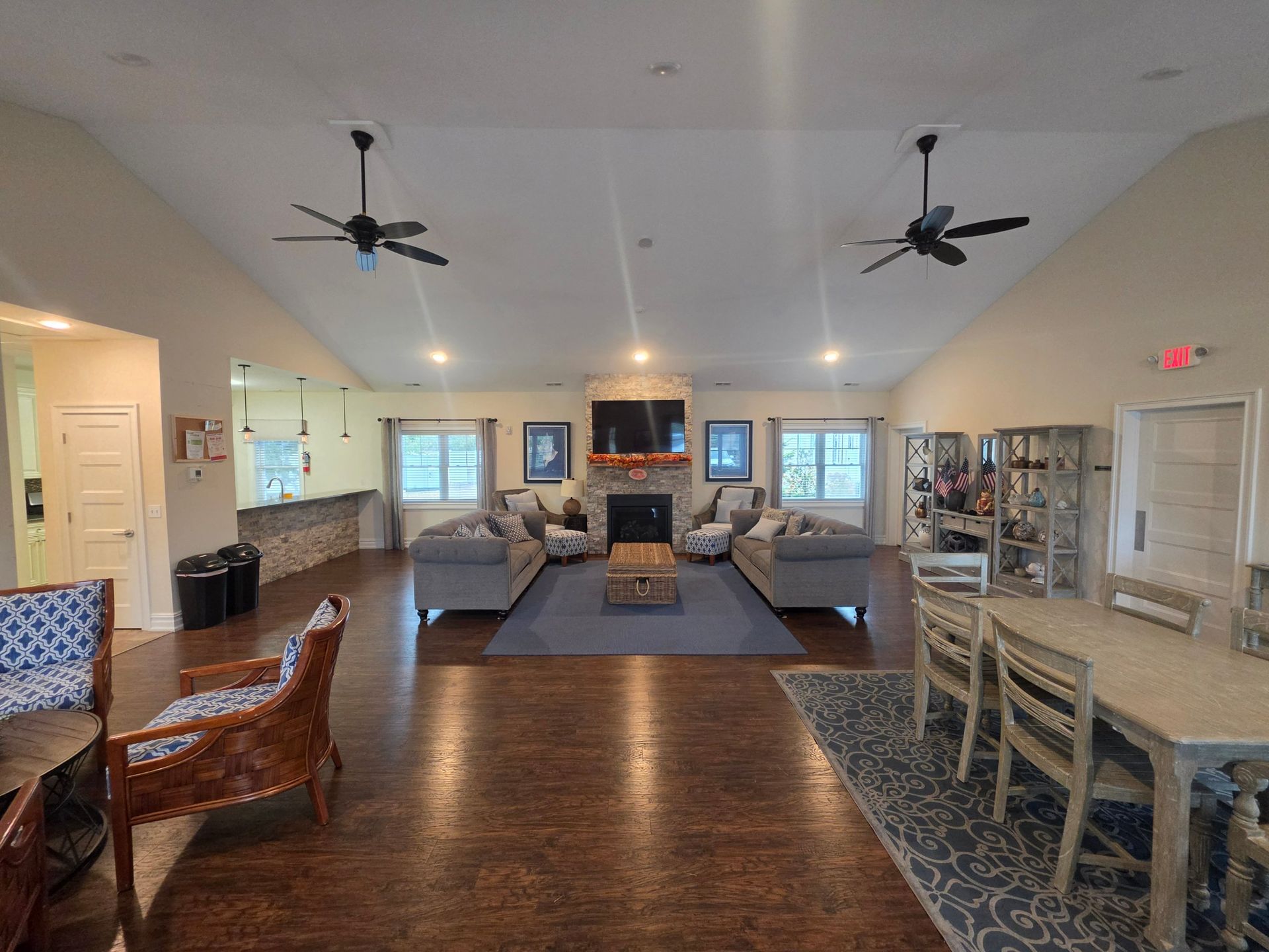 The clubhouse great room with a vaulted ceiling, stone fireplace, two facing sofas and ceiling fans