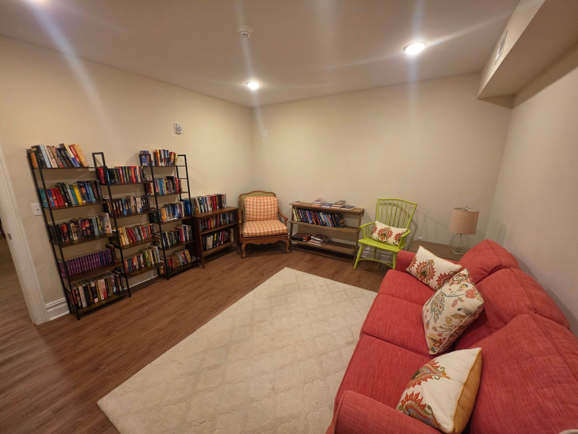 Clubhouse library lounge with shelves of books, a coral sofa and cozy chairs